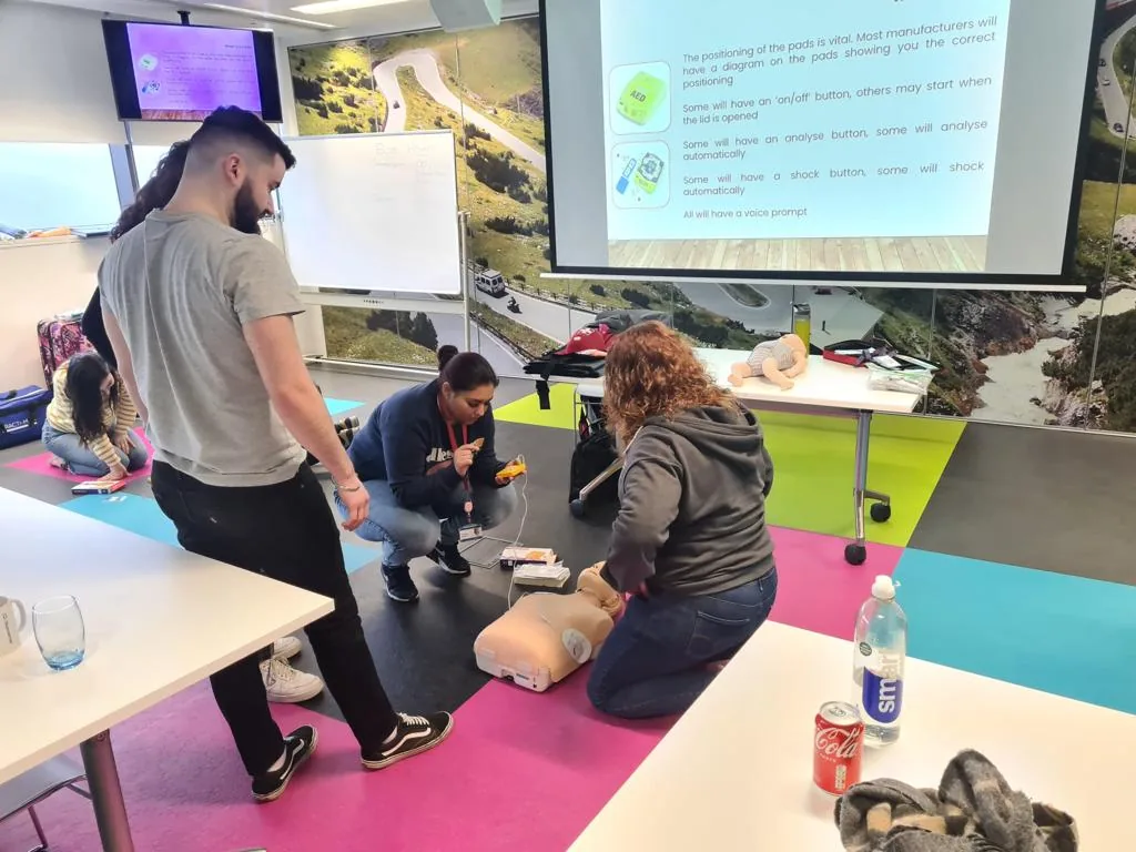 A trainer supervising learners as they practise first aid and using a defibrillator